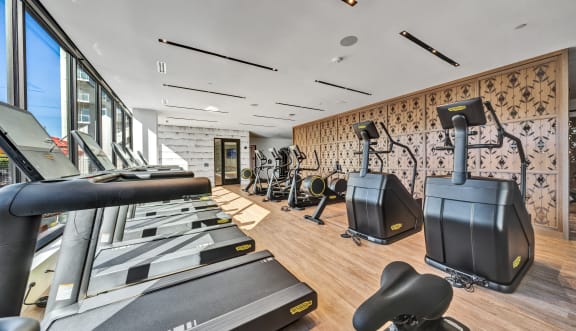 a gym with exercise equipment and large windows and a view of a pool at The Mera, St Louis Park, MN