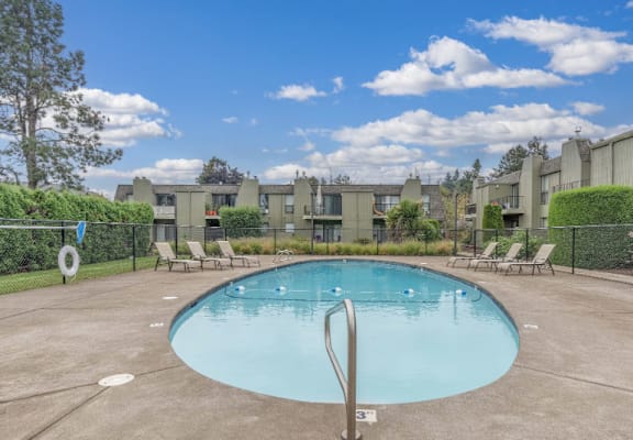 A swimming pool surrounded by a fence and chairs.