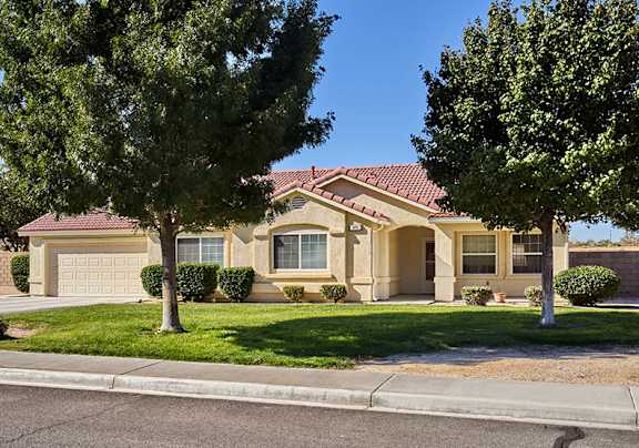A house with a brown roof and a tree in front.