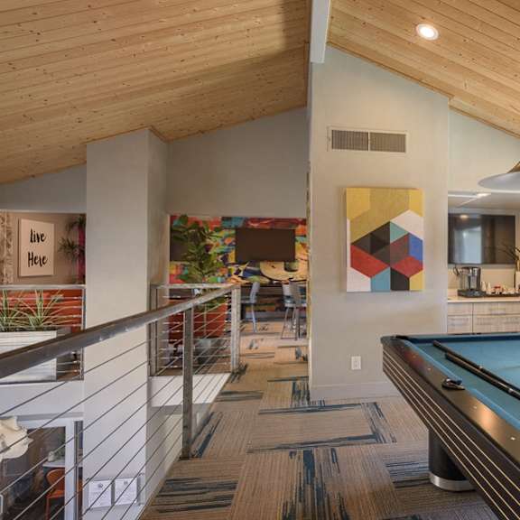 A pool table is in the middle of a room with a wooden ceiling.