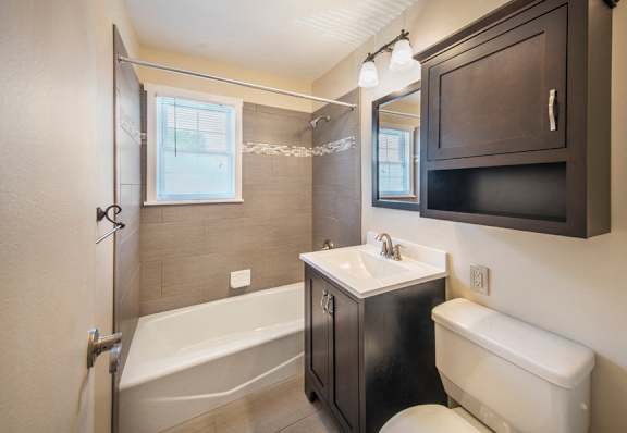 A bathroom with a white tub, sink, and toilet at Rivercrest Apartments, Piscataway  08854