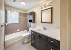 A bathroom with a white toilet, a bathtub, and a sink at Rivercrest Apartments, Piscataway