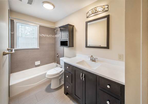 A bathroom with a white toilet, sink, and bathtub at Rivercrest Apartments, Piscataway , NJ