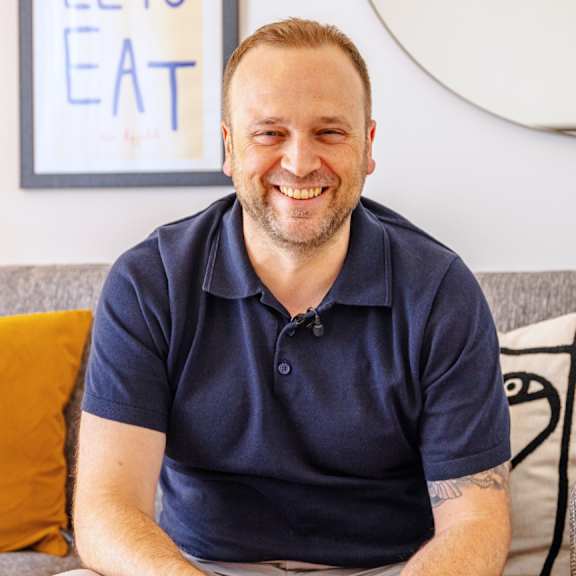 A man in a blue shirt is smiling at the camera.