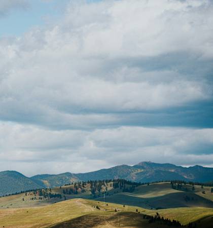 a field with mountains in the distance under a cloudy sky