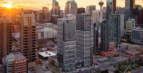 A cityscape with tall buildings and a sunset in the background.