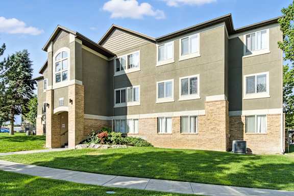 A large apartment building with a green lawn in front.