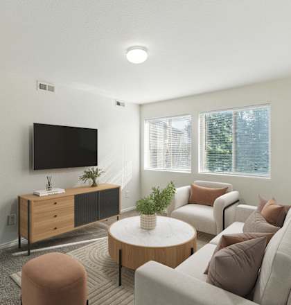 A living room with a brown couch, a brown ottoman, a white table, and a flat screen TV mounted on the wall.