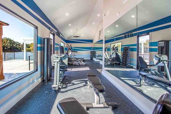 A gym with a row of treadmills and a row of stationary bikes.