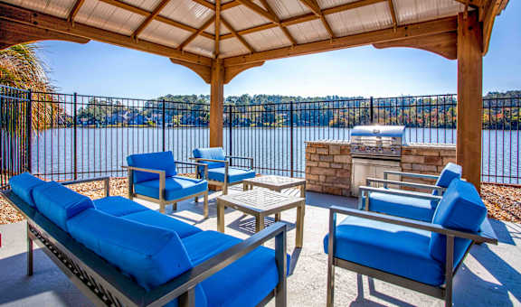 A patio with blue cushioned furniture overlooking a body of water.