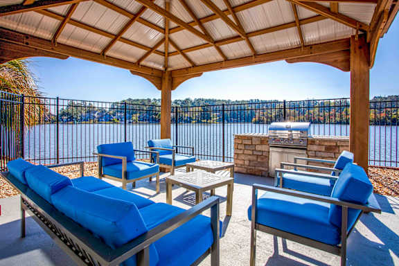 A patio with blue cushioned furniture overlooking a body of water.