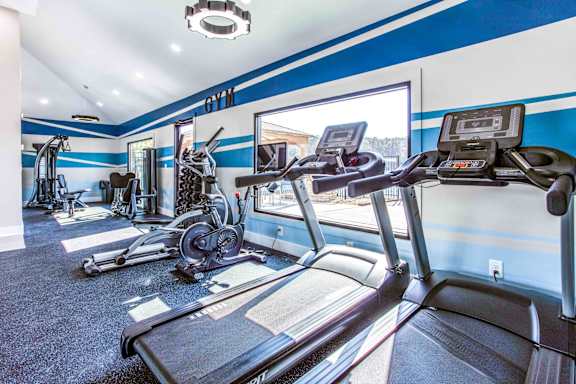 A treadmill in a gym with a view of the outside.