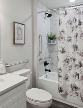 a bathtub with a shower curtain and a toilet in a 555 waverly unit