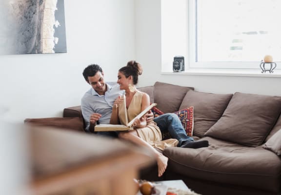 Couple Sitting on Couch Flipping Through Book
