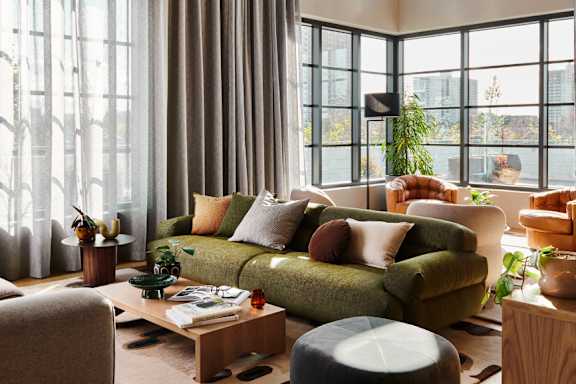 A living room with a green couch and a large window.