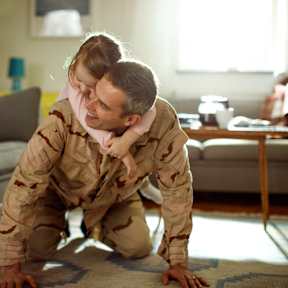 A man and a woman in military uniforms are playfully posing on the floor.