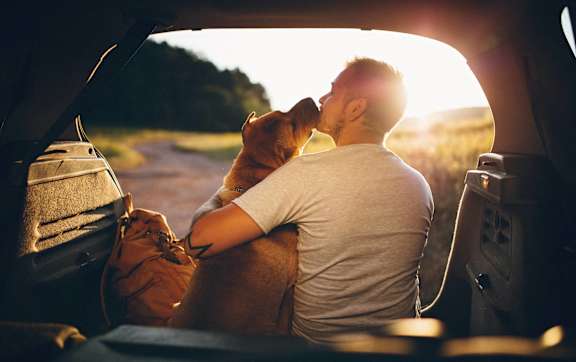 A man is sitting in a car with his dog.
