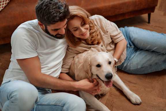 A man and woman sitting on the floor with a dog.