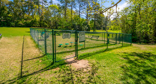 a chain link fence with a dog park behind it