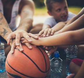 A group of people are holding hands around a basketball at Victory Northgate Apartments, Seattle, Washington