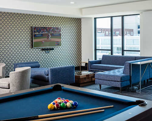 A pool table with a television playing baseball behind it.