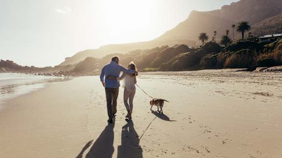 A man and woman walking a dog on a beach.at Panorama Riverpark, Oxnard, 93036