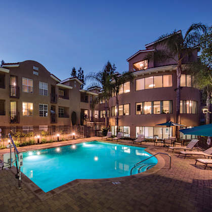 A swimming pool surrounded by lounge chairs and umbrellas at a resort.