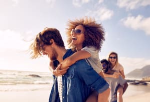 a man carrying a woman on the beach with other people