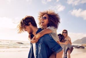 a man carrying a woman on the beach with other people