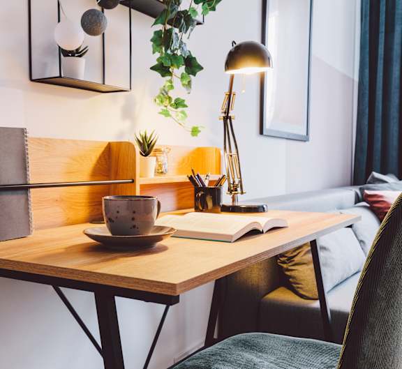 A table with a lamp, a book, and a cup on it.