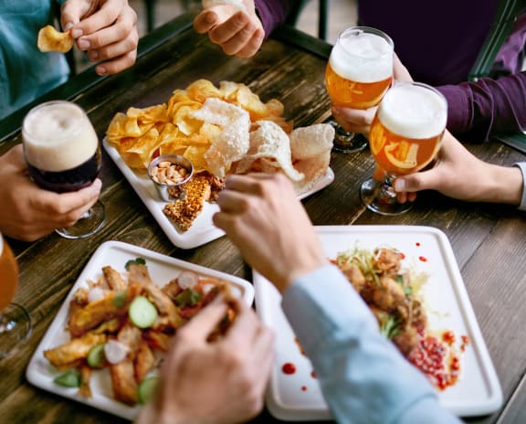 people sitting around a table eating food and drinking beer