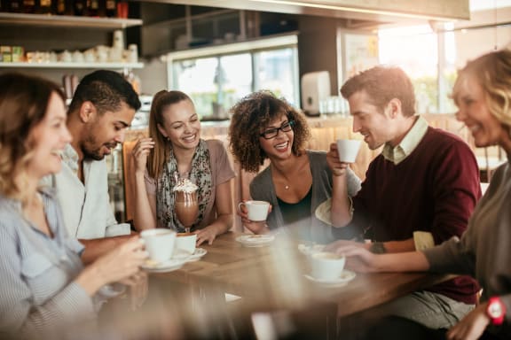 a group of people sitting at a table drinking coffee