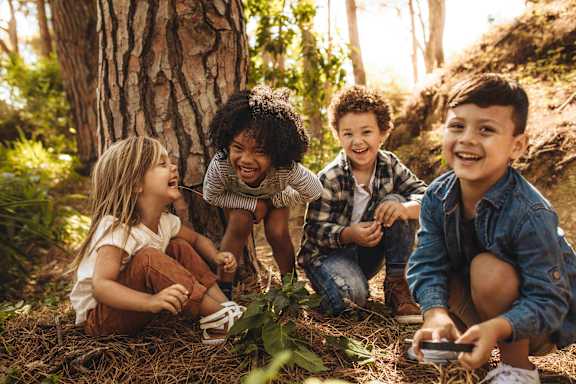 Four children are playing in the woods at The Foundry Apartments, Bordon, GU35 9FE