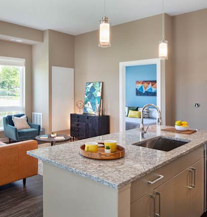 A kitchen with a sink, a counter, and a couch.