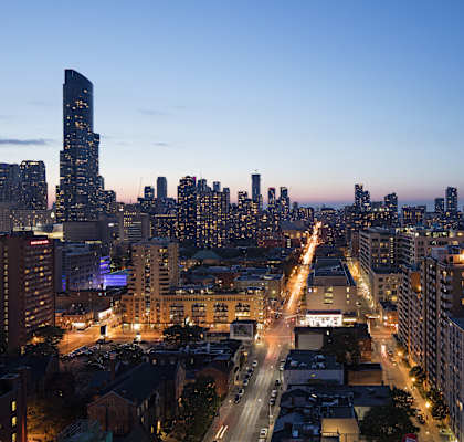 A cityscape at dusk with buildings and streets illuminated.