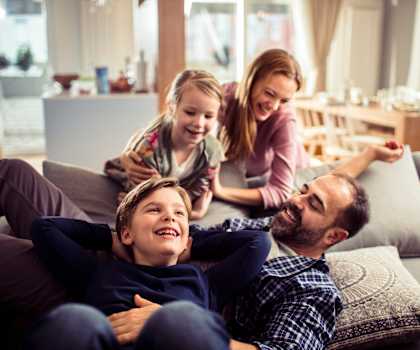 A family of four is sitting on a couch in a living room.