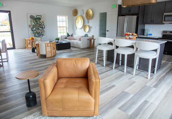 A living room with a tan leather chair and a grey floor.