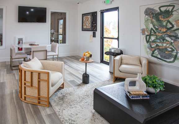 A living room with a black coffee table and a large painting on the wall.