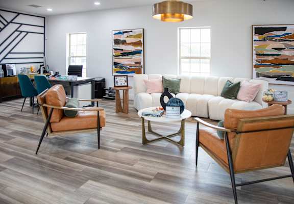 A living room with a white couch and brown chairs.
