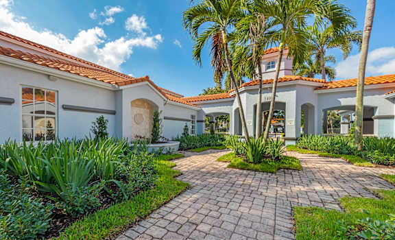 A house with a red tile roof and a brick walkway in front.