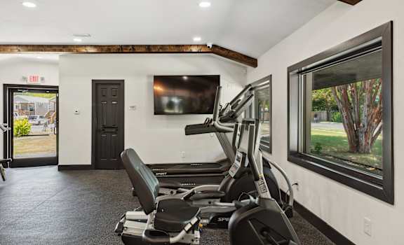 A gym room with a treadmill and a window.