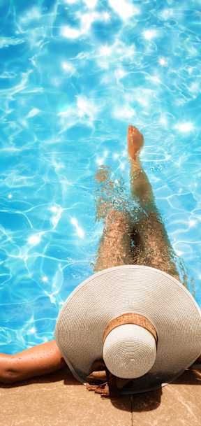 A woman in a white hat is floating in a pool.