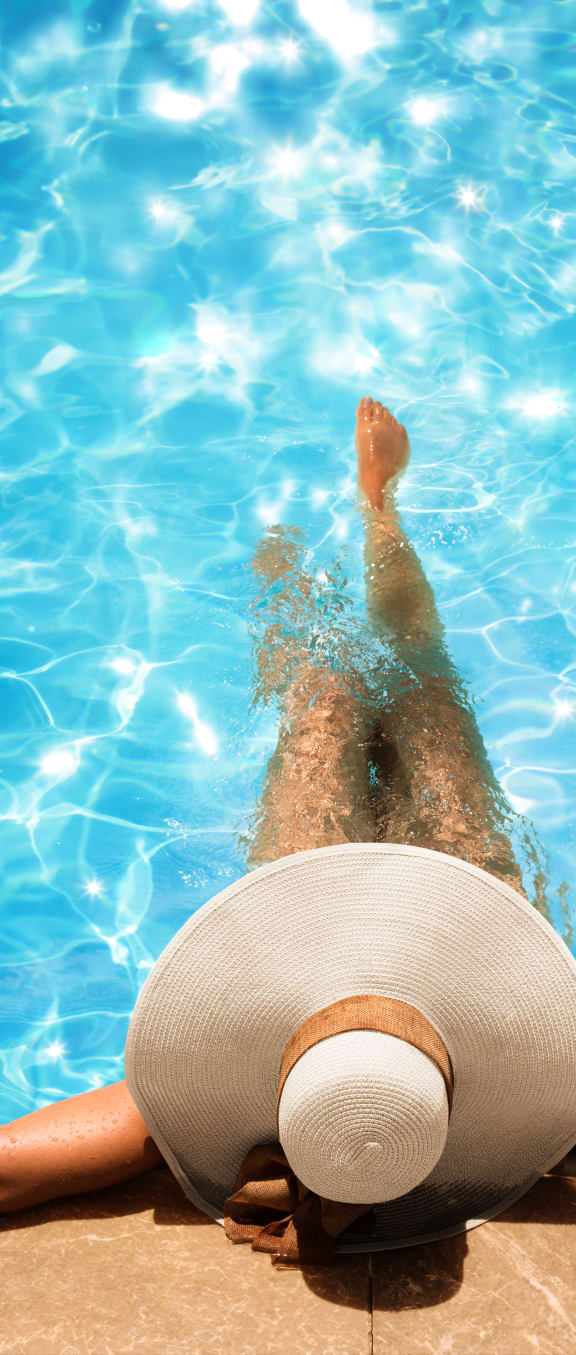 a woman in a hat laying on her back in a pool