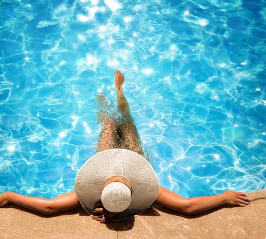 a woman in a hat laying in a pool