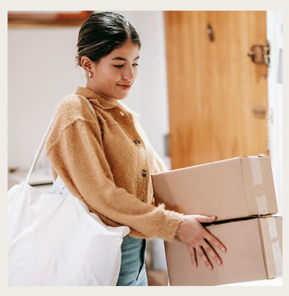 A woman is carrying a box and a bag.