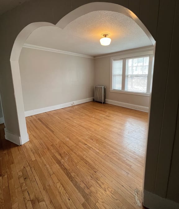 an empty room with hardwood floors and an archway