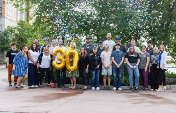 a group of people posing for a photo in front of a tree