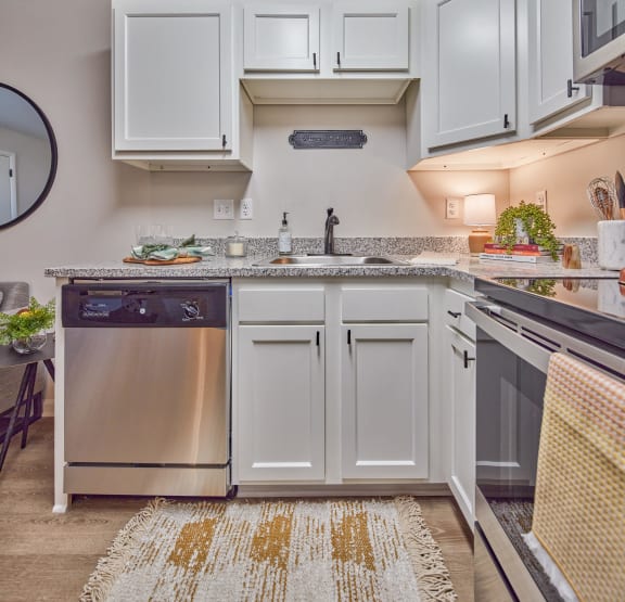 a kitchen with white cabinets and a stainless steel dishwasher and sink