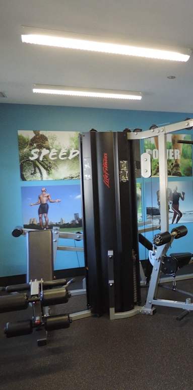 A gym with a rowing machine and a wall with posters.