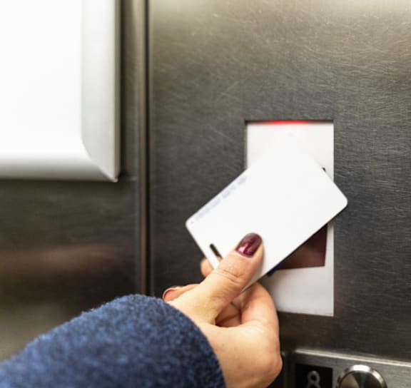 A person is inserting a card into a metallic elevator.